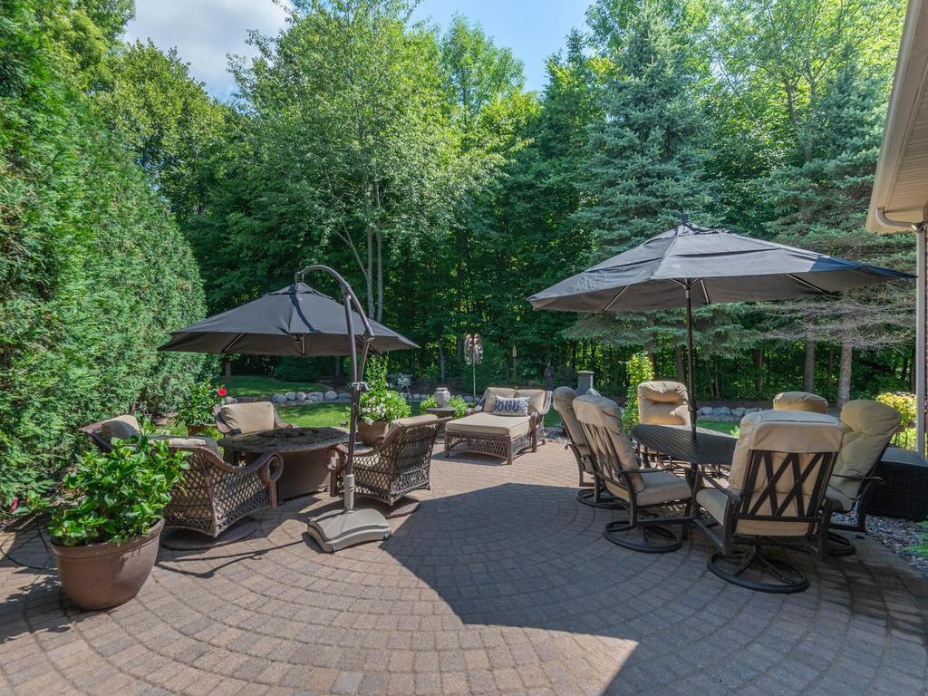 Expansive paver patio located just off the formal dining room offers multiple seating and dining areas surrounded by mature trees and landscaped gardens.