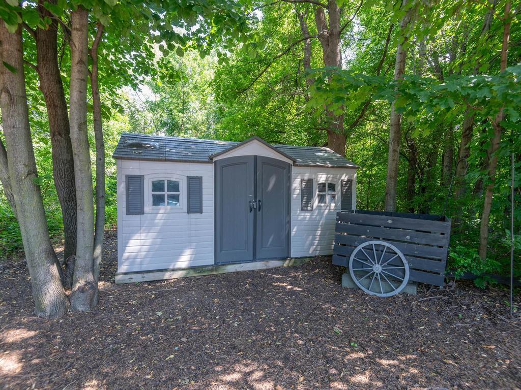 14x8 windowed storage shed tucked into the trees provides convenient space for lawn, garden, and outdoor equipment.