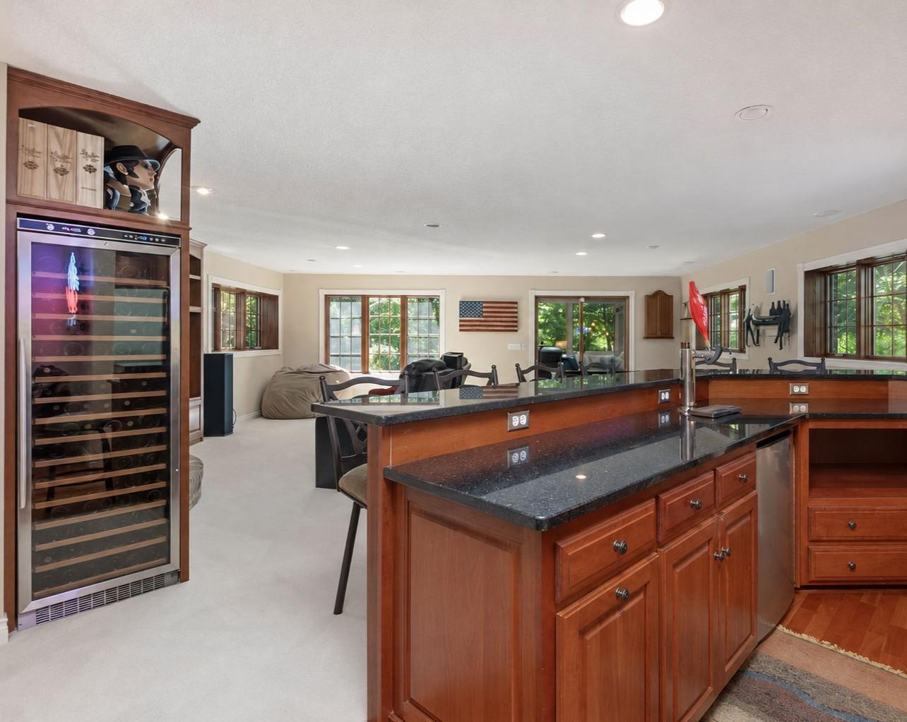 Lower level wet bar overlooks the expansive family and entertainment area, creating an open setting for gathering. Photo AI-enhanced for lighting and presentation; property features remain unchanged.