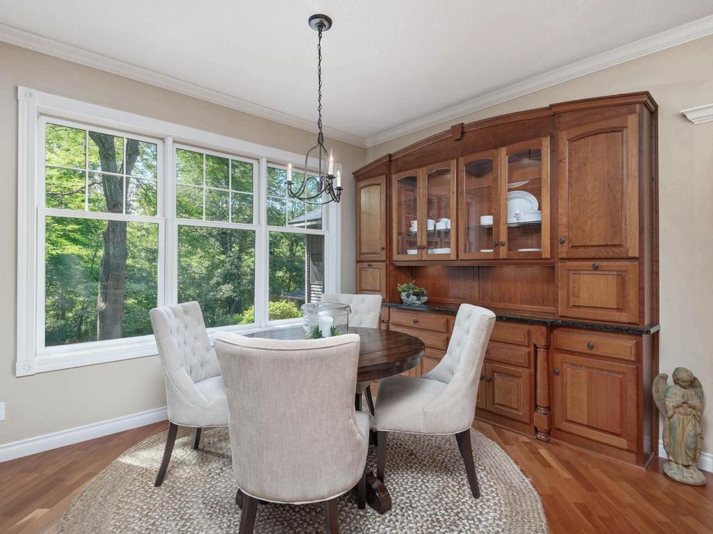 Informal dining area features hardwood flooring, built-in buffet, wooded views, and the shared 3-sided stone gas fireplace.
