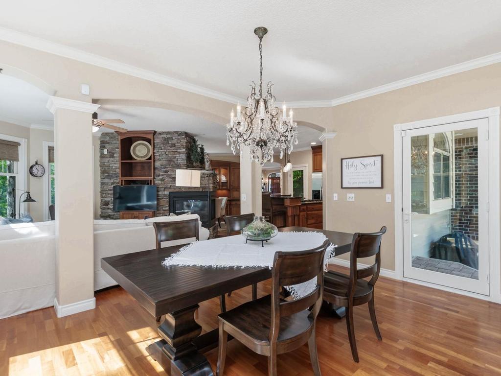 Open main level layout connects the formal dining room, great room, hearth room, and kitchen, while the glass door provides direct access to the paver patio and outdoor dining areas.