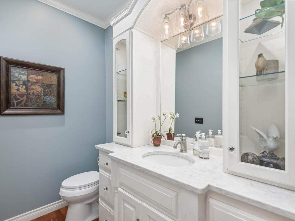 Main level Half Bath features a built-in glass display cabinetry, crown molding, and hardwood flooring.