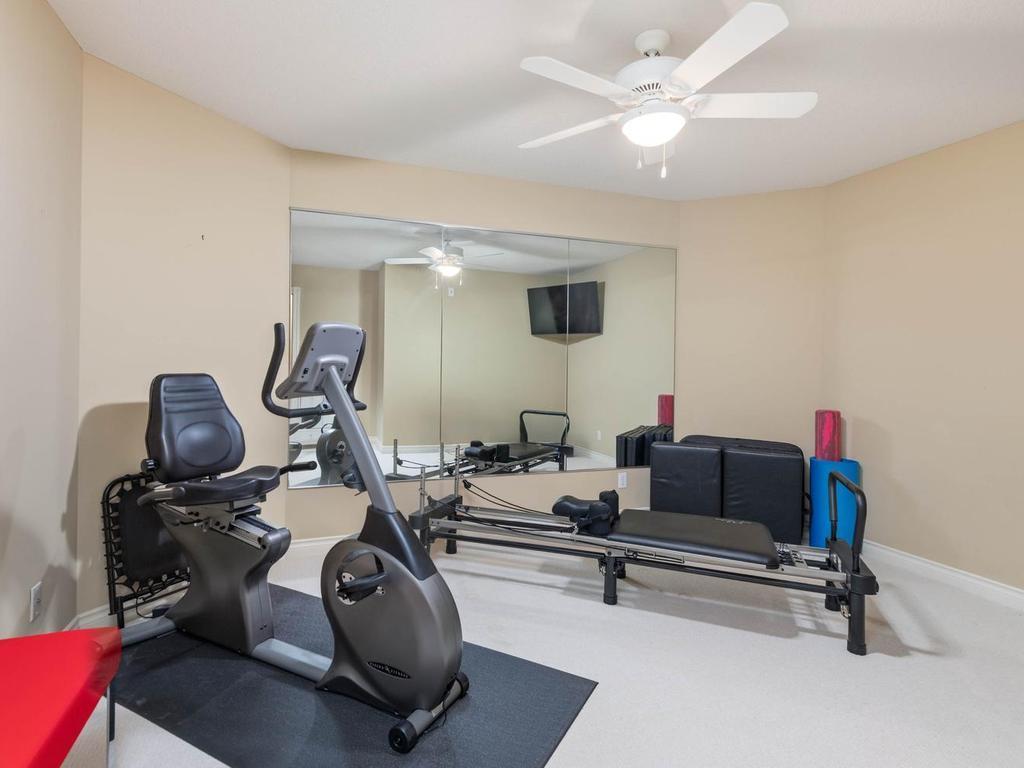 Lower level Flex Room offers adaptable space for exercise, hobbies, storage, etc. with a mirrored wall, ceiling fan, and neutral finishes.