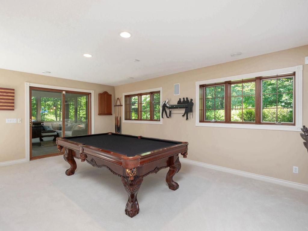 Lower level pool-table area offers generous recreation space, recessed lighting, wooded views, and direct access to the 3+ season screened porch.