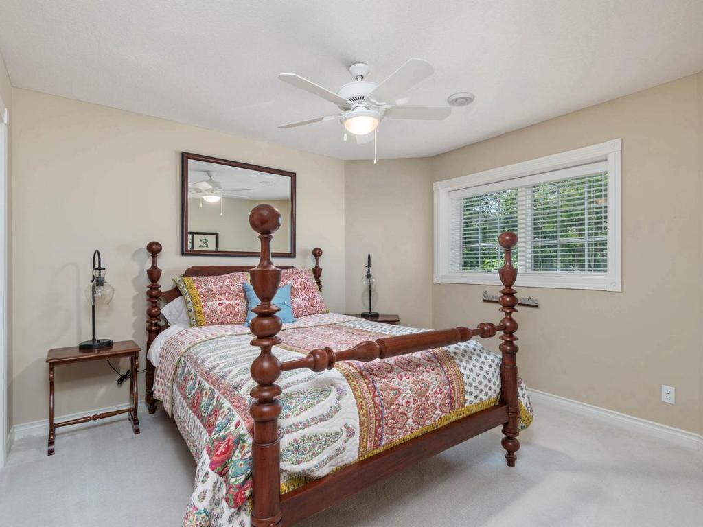Lower level Bedroom 4 features a ceiling fan, neutral finishes, and a window overlooking the wooded setting.