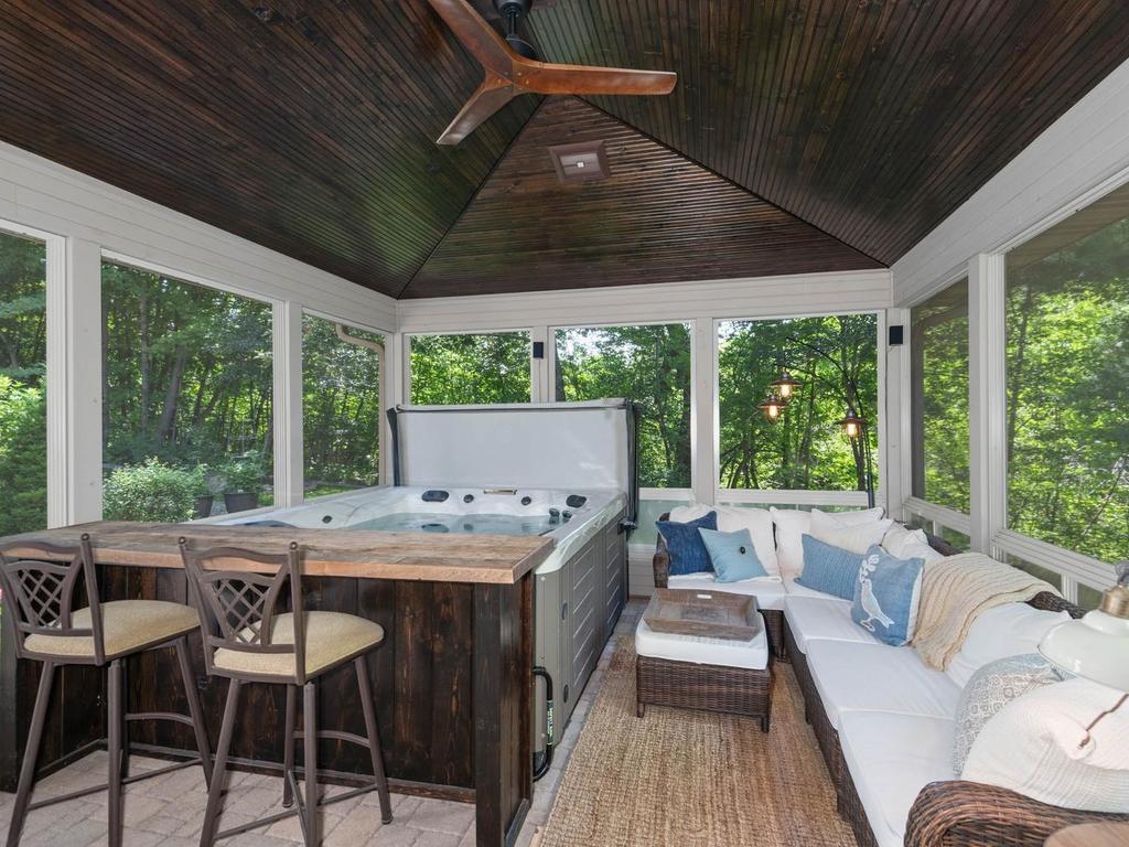 Exceptional 270 sq ft 3+ season screened porch offers highly usable bonus space w/hot tub, vaulted wood ceiling, ceiling fan, expansive screened windows, paver floor, and immersive wooded views; not included in the home’s finished sq ft.