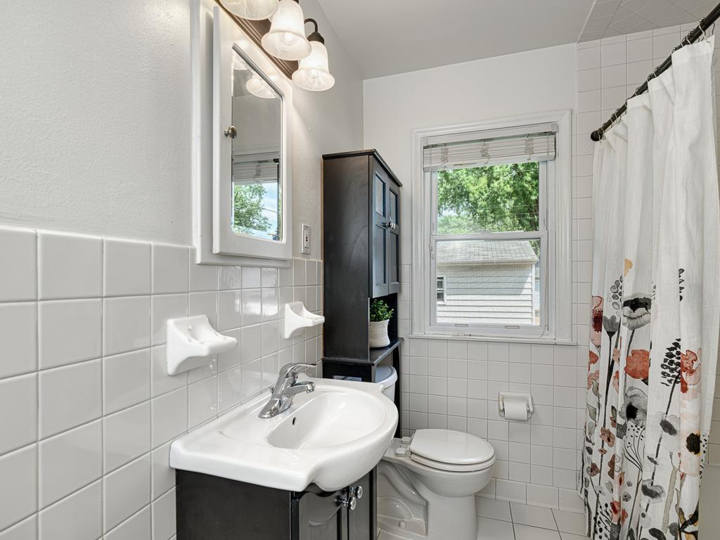The bright white tiled full bathroom on the main level.