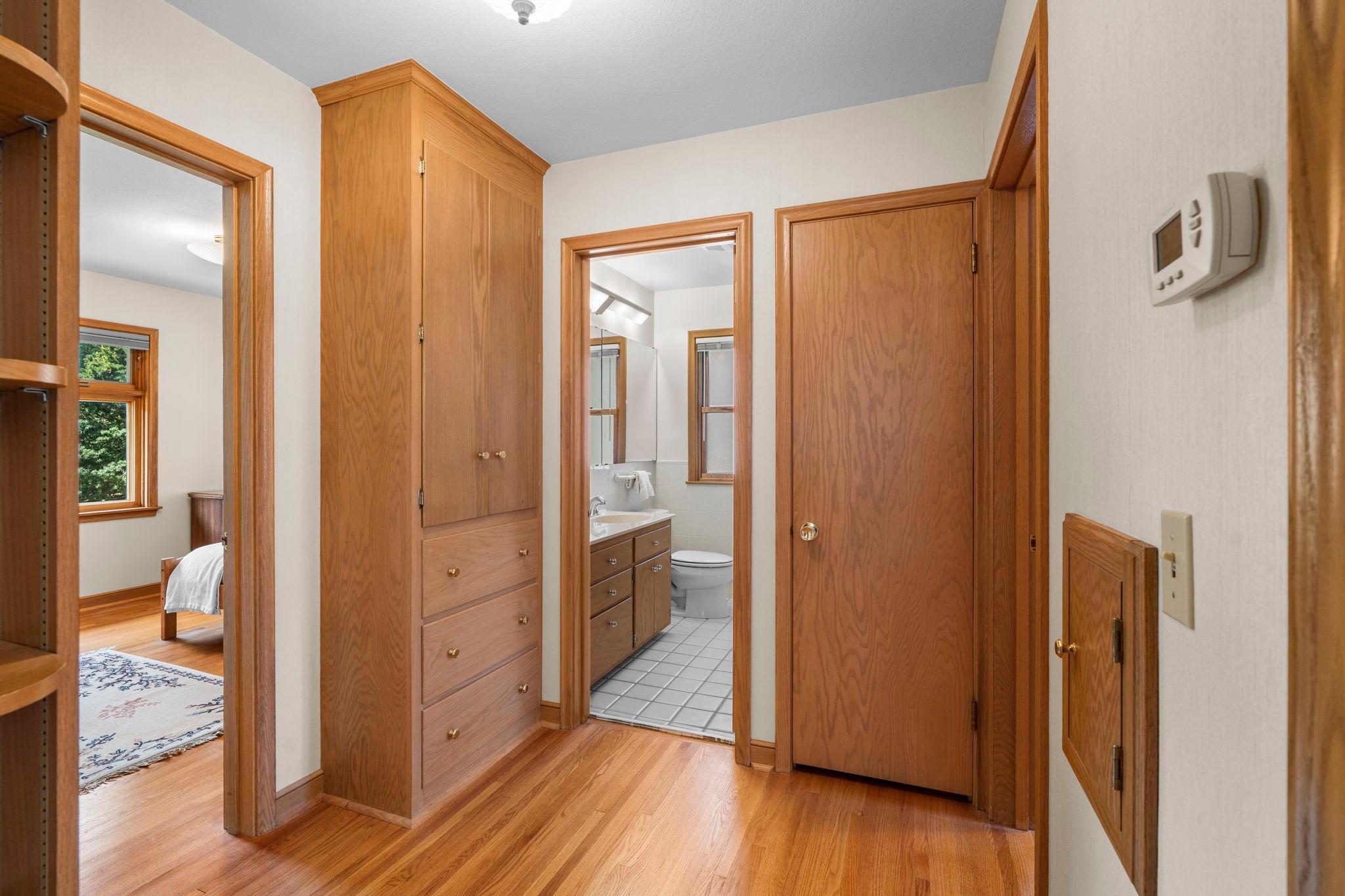 Abundant hallway storage with built-in shelving, cabinets, and closet.