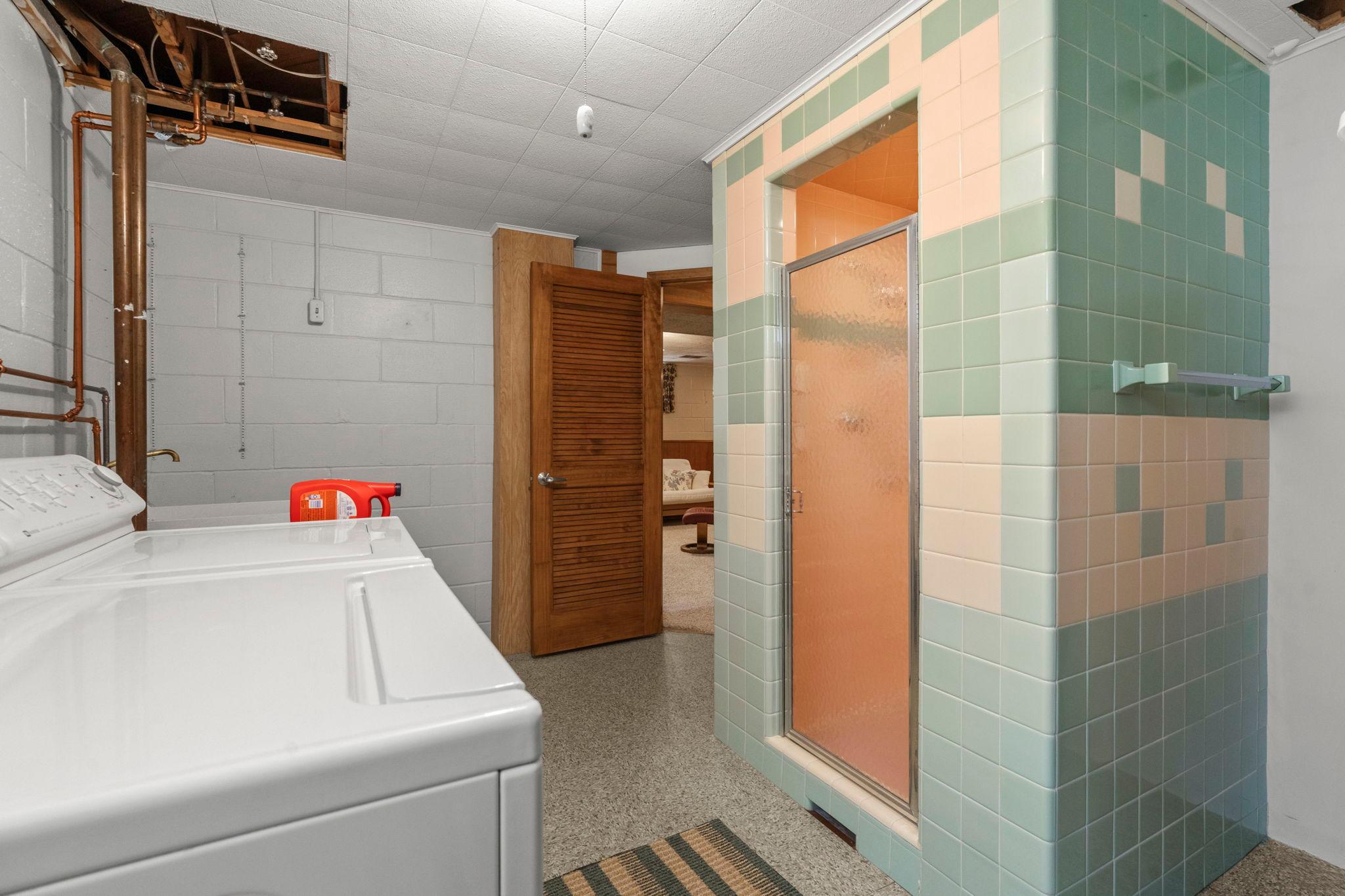 A finished laundry room that includes a Maytag washer and dryer, utility sink, walk-in shower, and storage complete the lower level.