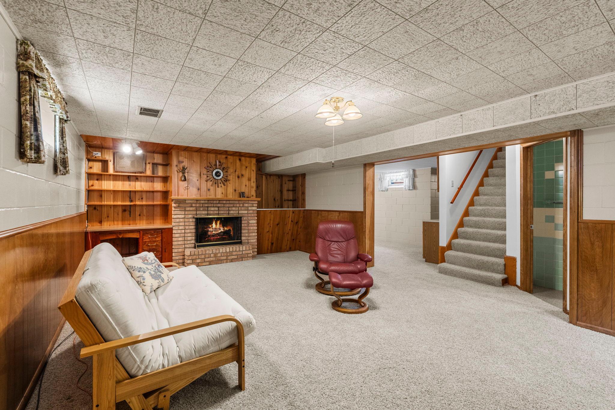 The spacious family room features another wood-burning fireplace, warm wood accents, a built-in workspace, and plenty of room for gathering or relaxing.