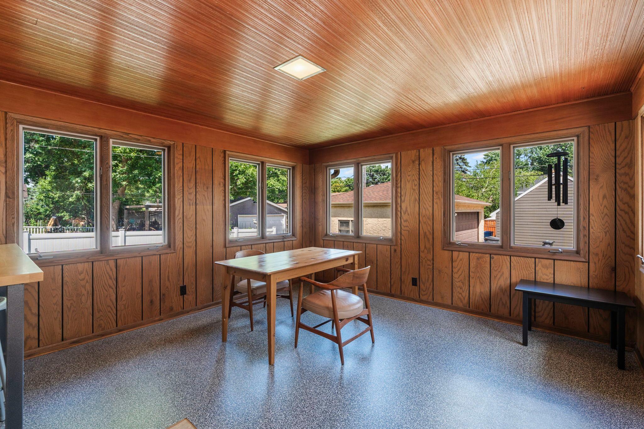 The inviting sunroom is another standout space, where wood-paneled walls create a cozy atmosphere and backyard access makes indoor and outdoor living feel naturally connected.