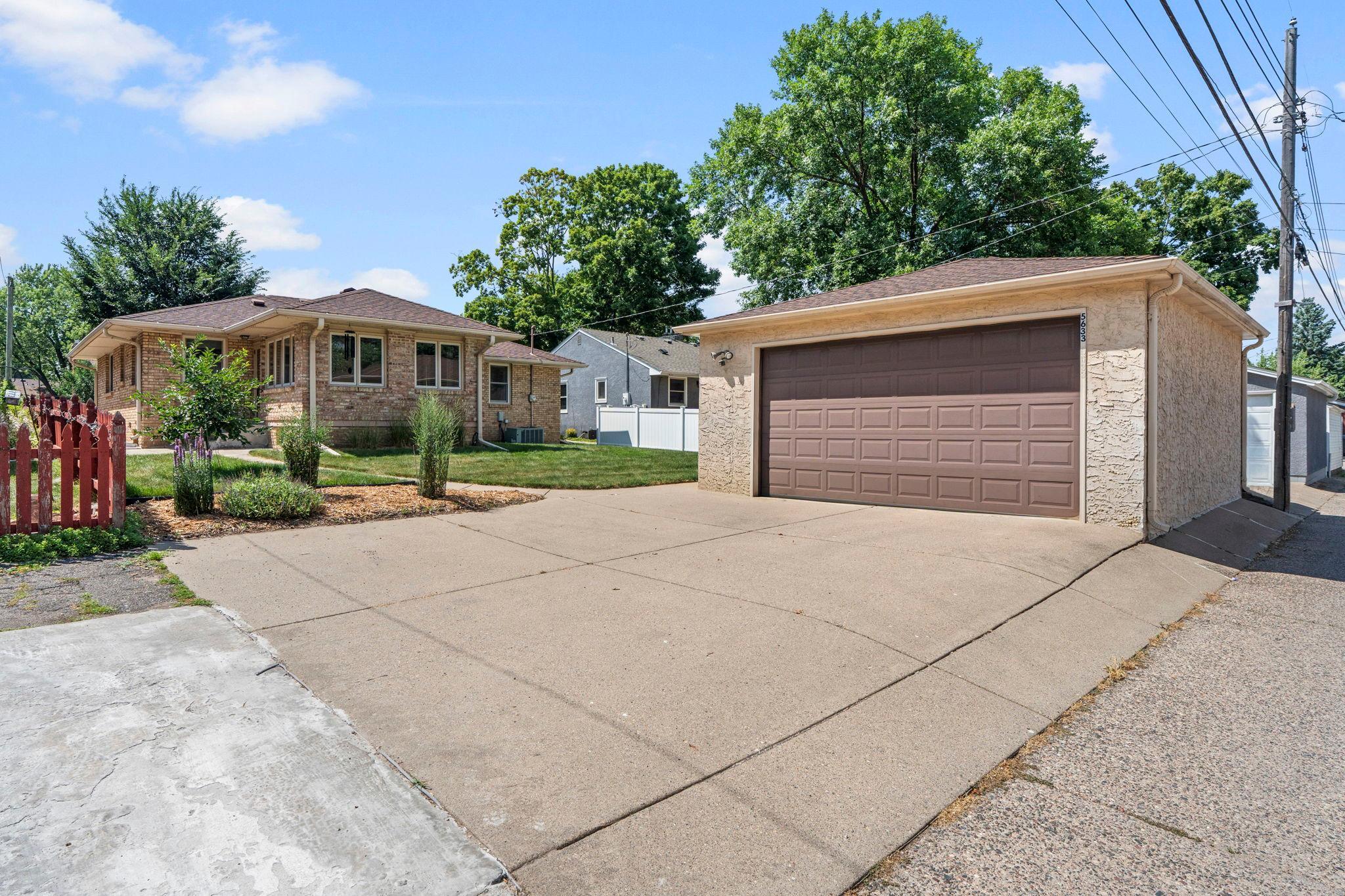 A detached two-car garage is paired with an oversized parking pad for extra vehicles or guests.