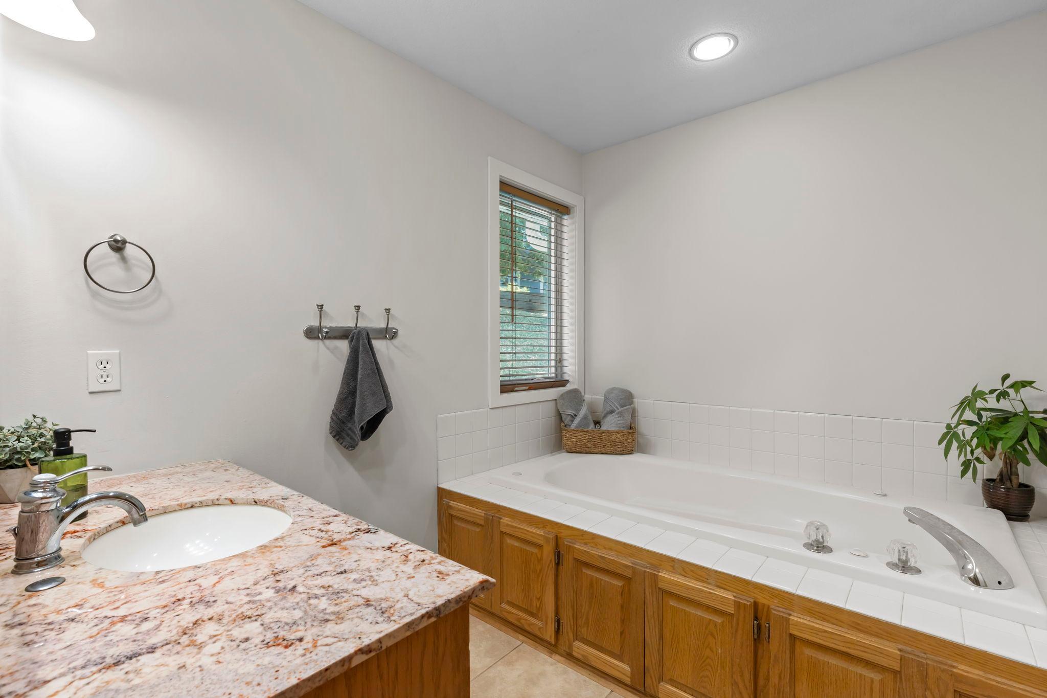 Private bath featuring a jetted soaking tub, walk-in shower, and vanity storage.