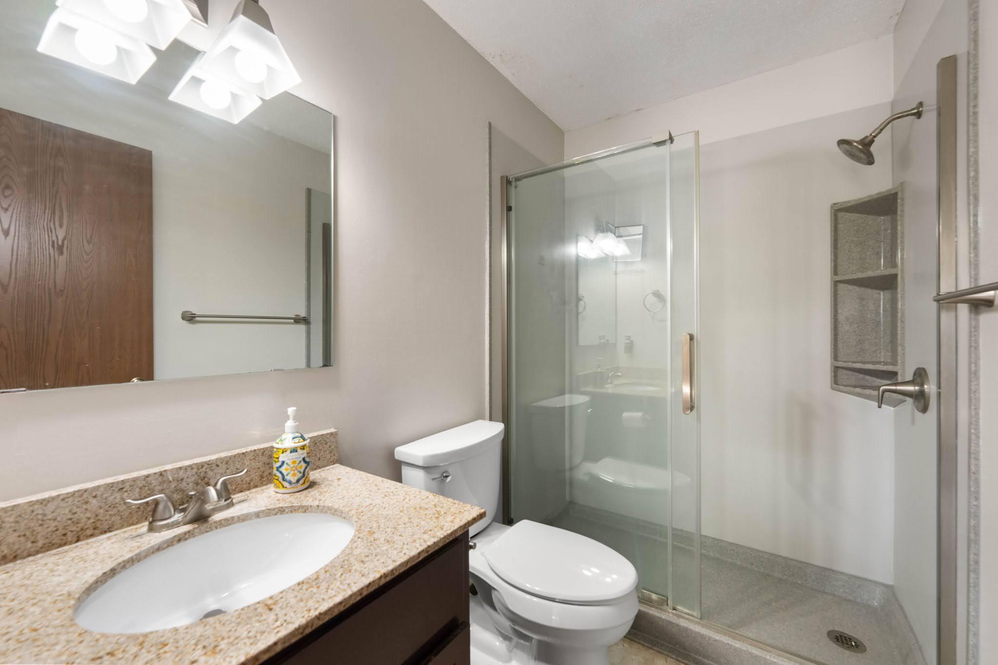 Main condo bathroom with updated granite counters and new walk-in shower