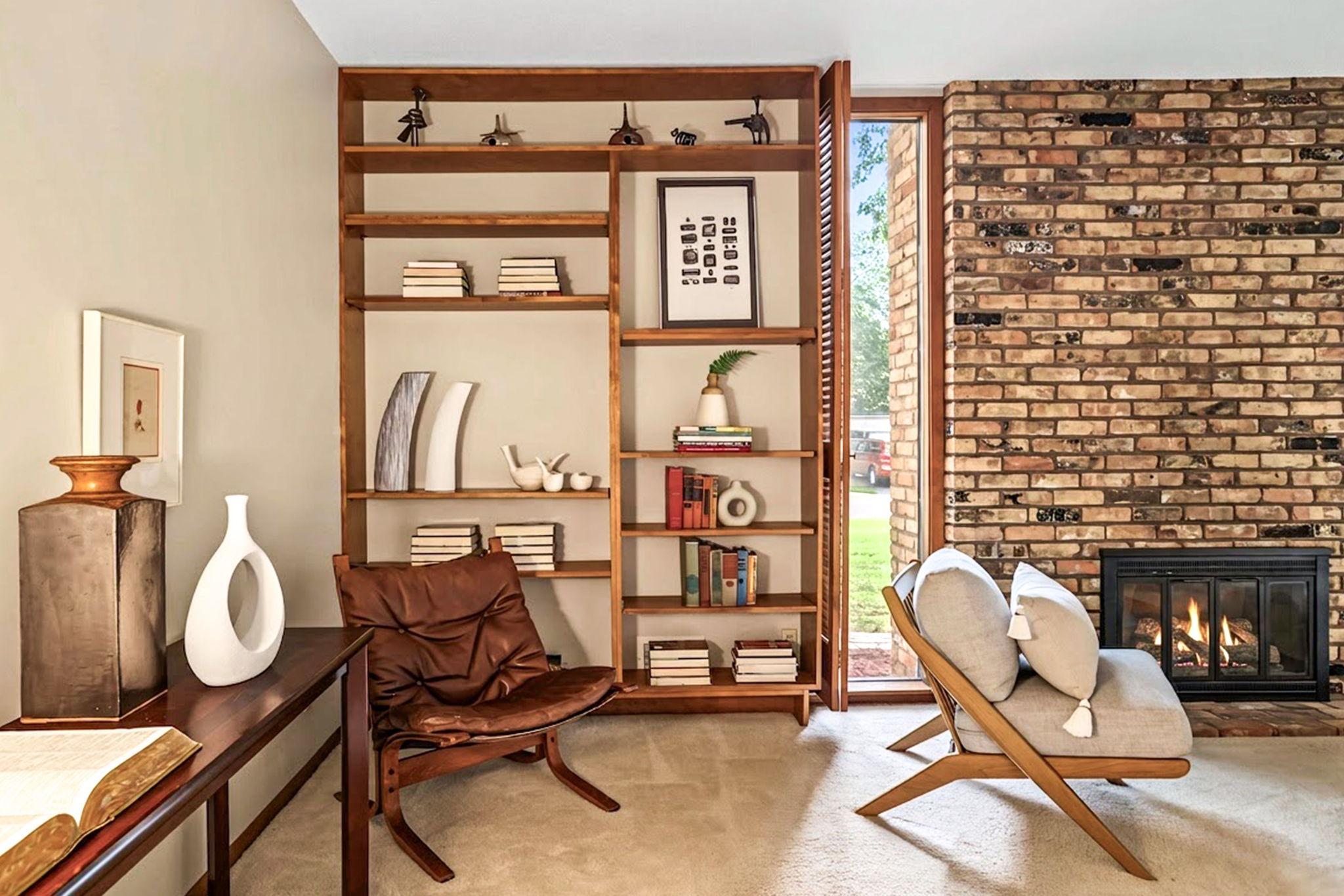 Living room with a wood burning fireplace and wall of built-in bookshelves.