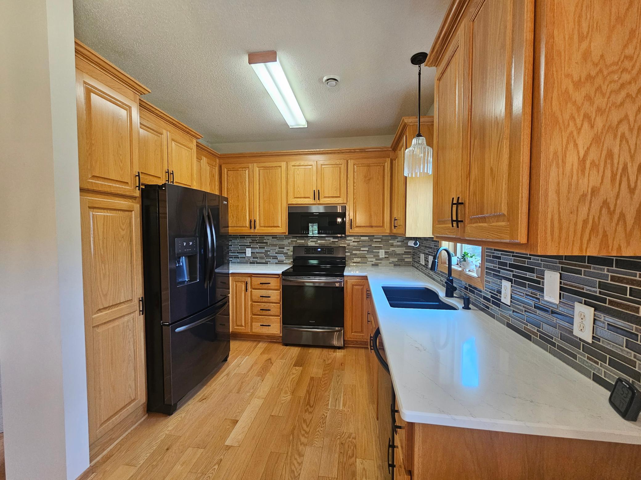 Kitchen features newer black stainless appliances and tiled backsplash.