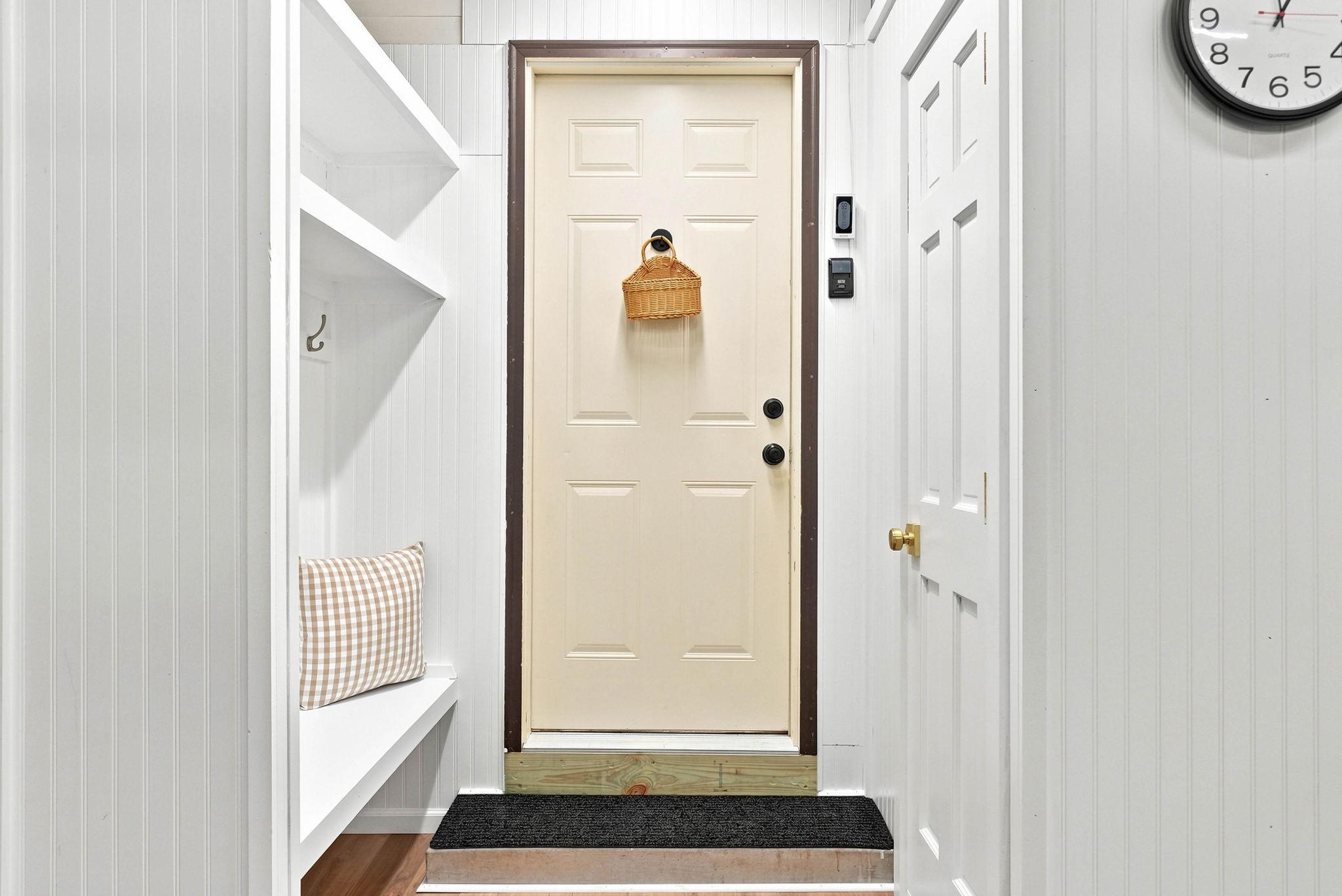 Sellers created this small mudroom in the garage with a built-in bench, coat hangers, and closet space before entering the home.