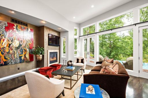 Walls of windows bring the outdoors in, filling the main level living room with natural light while framing the home's serene, wooded setting. Brazilian cherry hardwood floors and a sleek fireplace add warmth to the open concept design.