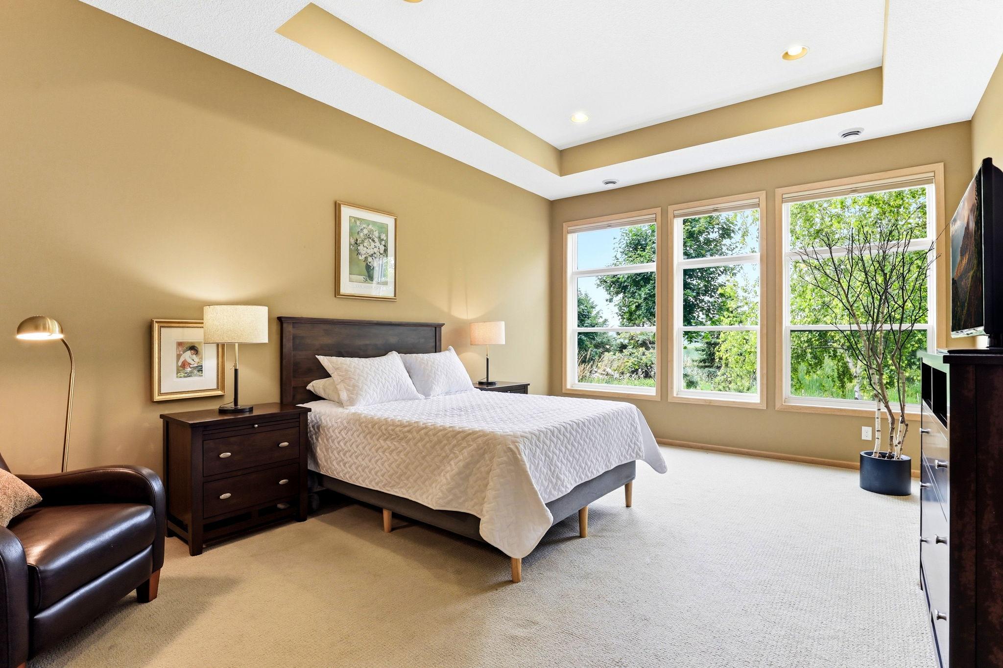 Primary suite showcases a serene retreat with a private bath, a spacious walk-in closet, and an elegant tray ceiling.