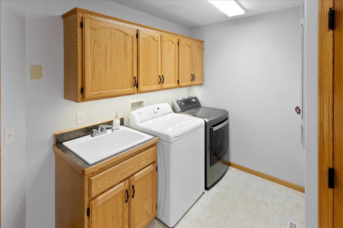main floor laundry with cabinets and laundry sink