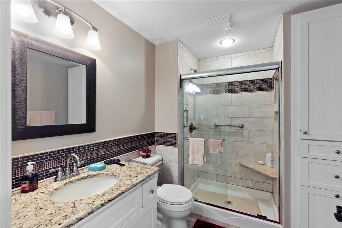 Lower Level bathroom with glass shower doors, tile surround and granite vanity