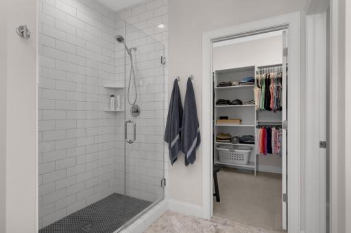 Primary bath features a large tiled walk in shower and walk in closet with organizers.