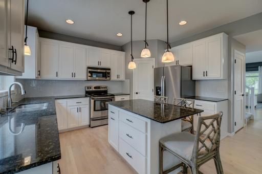 The updated kitchen features granite countertops, stainless steel appliances, a stylish new tile backsplash, and ample prep space!