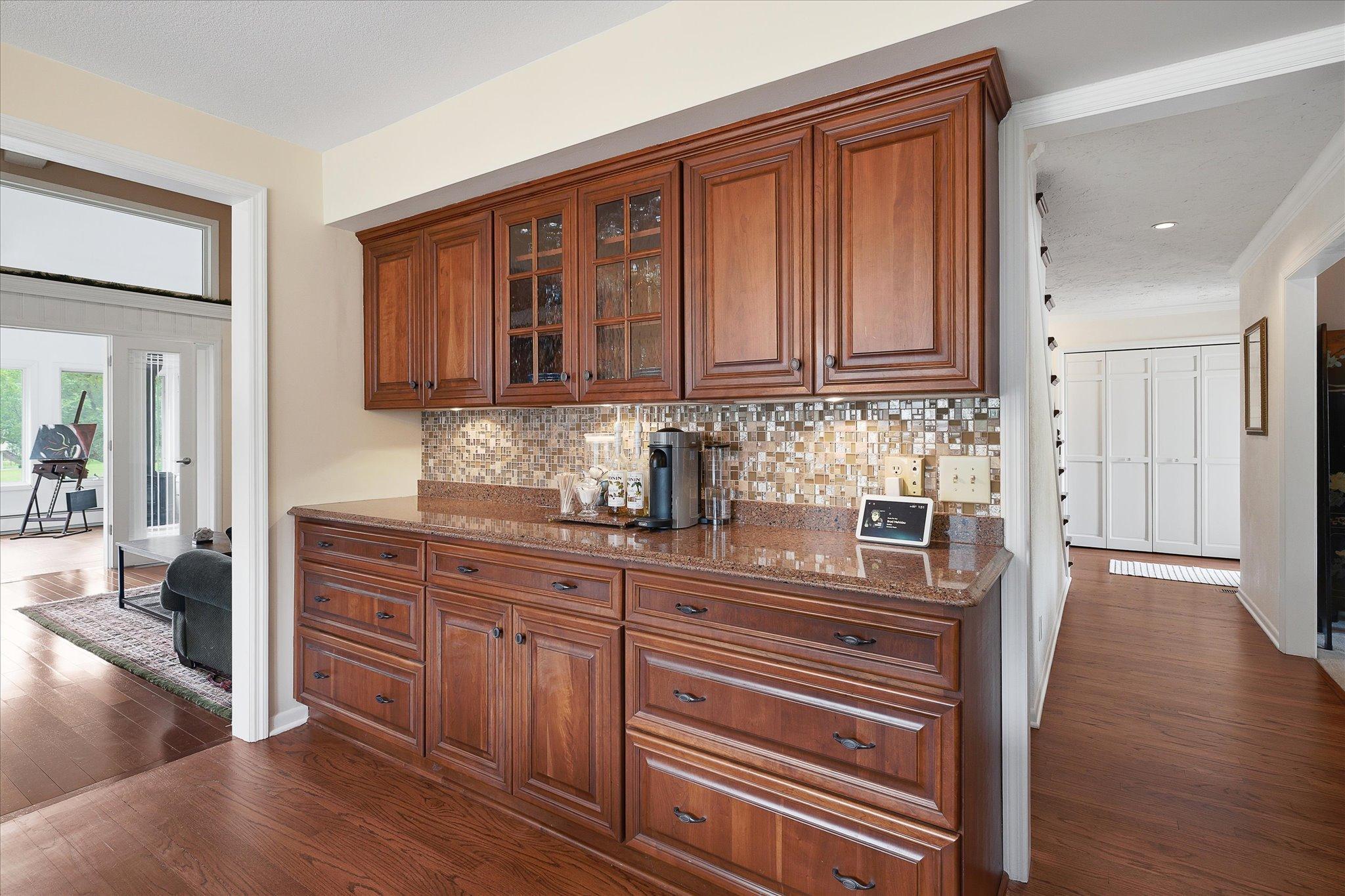 Wood cabinetry including glass inserts and tiled backsplash adds a touch of elegance.