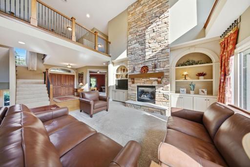 The sun-filled living room is anchored by a floor-to-ceiling stone fireplace framed by sleek built-ins.