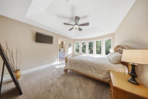 The luxurious main-level owner's suite overlooks the pond and features a refreshing ensuite bath with heated floors, dual vanities, a walk-in shower, and a spacious walk-in closet.