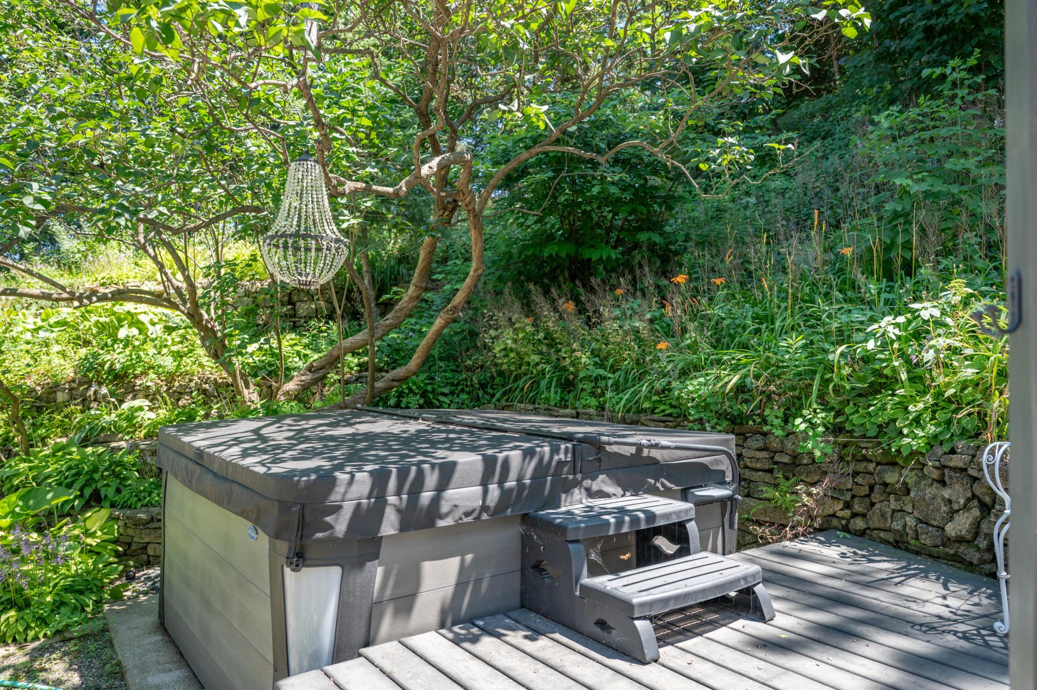 Much like the pool on the opposite side of the home, the hot tub area provides an oasis of calm with lush plantings and rustic stone walls.