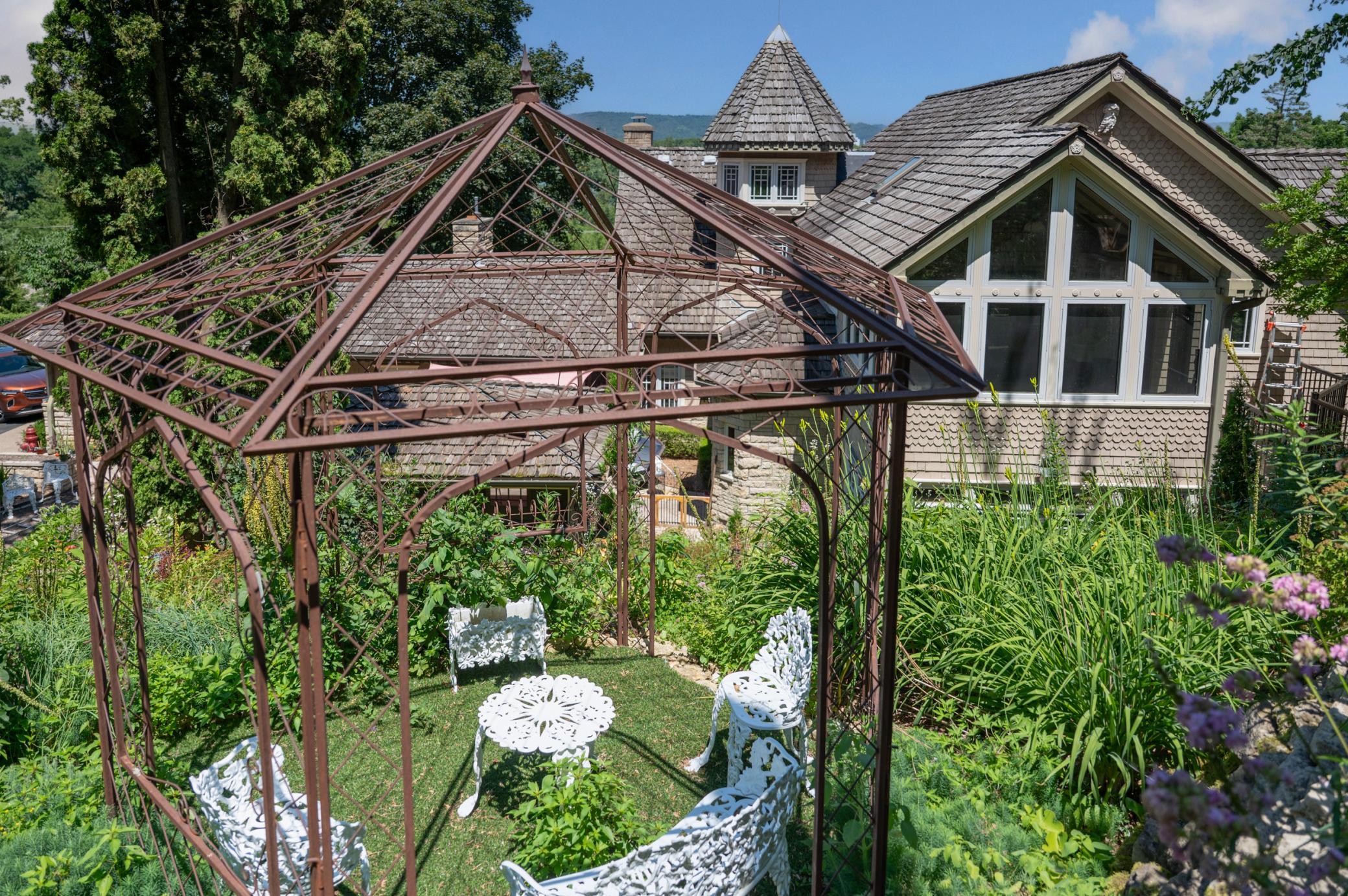 A pergola sitting area on the hillside is a great place to enjoy a cup of coffee or conversation with a friend. The large windows at right of frame are the greenhouse/sunroom space off the back of the second level.