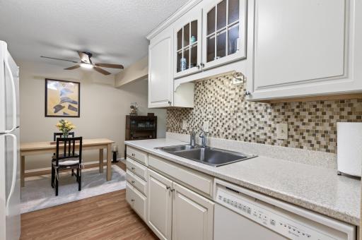 The tiled backsplash compliments the neutral kitchen, and wood grain vinyl flooring.