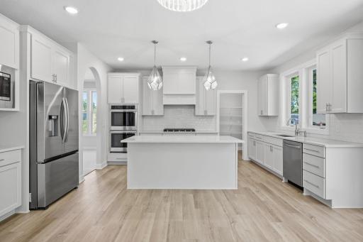 A closer look at the gourmet kitchen, featuring quartz countertops, a center island, stainless steel appliances, access to the impressive 15' x 6' walk-in pantry, and the formal dining room to the left.