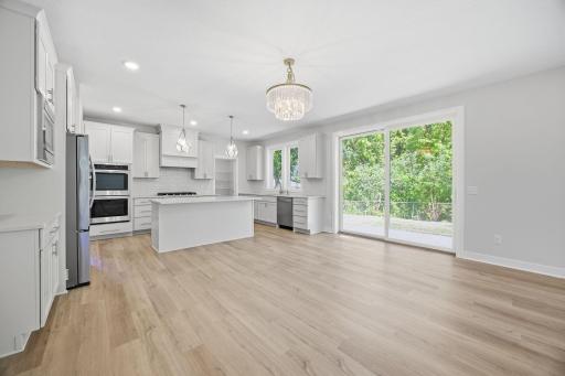 The gourmet kitchen is featuring quartz countertops, a center island with a breakfast bar, a porcelain tile backsplash, stainless steel appliances, and an extraordinary 15' x 6' walk-in pantry.