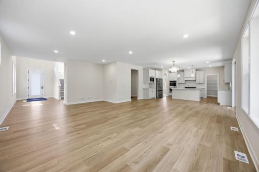 The foyer opens to a light-filled living room, informal dining area, and kitchen, creating an inviting open-concept living space.