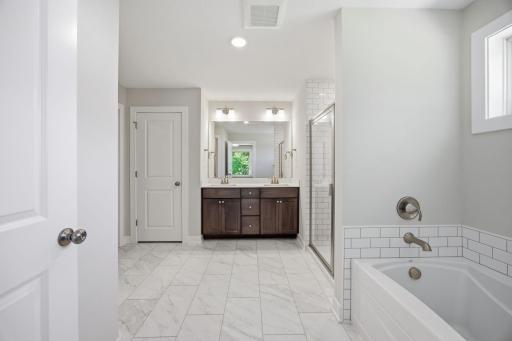 Primary luxurious private bath with a soaking tub, walk-in shower, dual vanities, and a large walk-in dressing room.