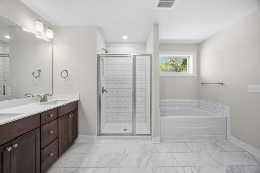 Another view of the primary luxurious private bath with a soaking tub, walk-in shower, dual vanities, and a large walk-in dressing room.