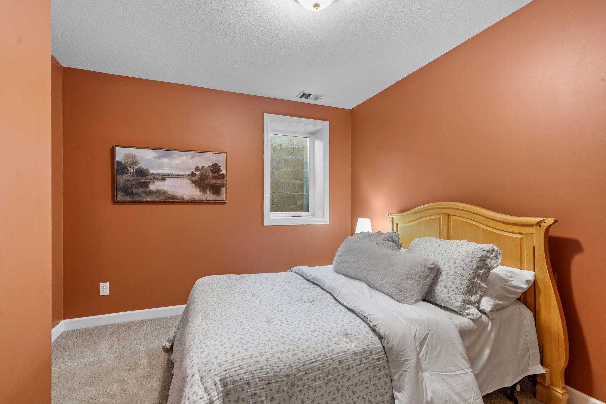 Lower level bedroom with egress window and small office setup in closet.