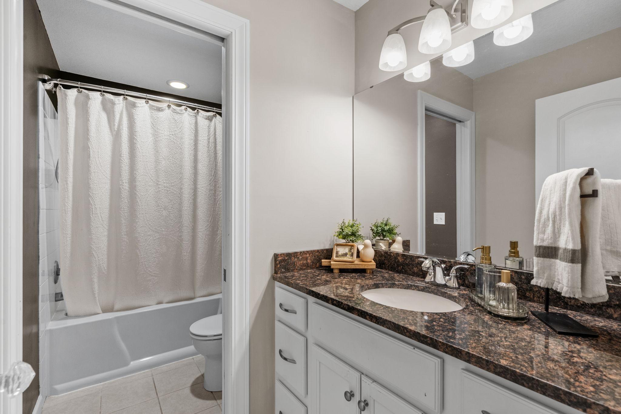Lower-level full bath with pocket door for added privacy.