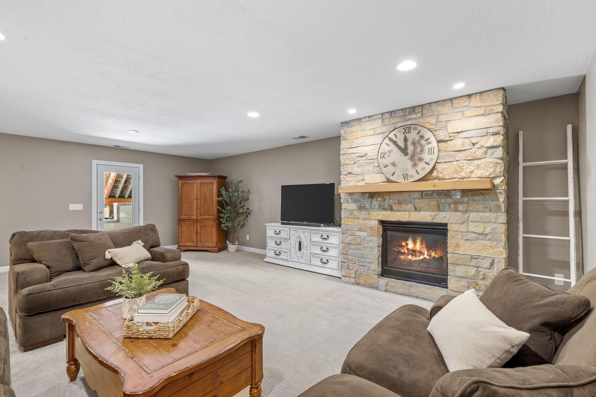 Beautiful floor-to-ceiling stone fireplace creates a warm and inviting focal point for the lower-level living space.