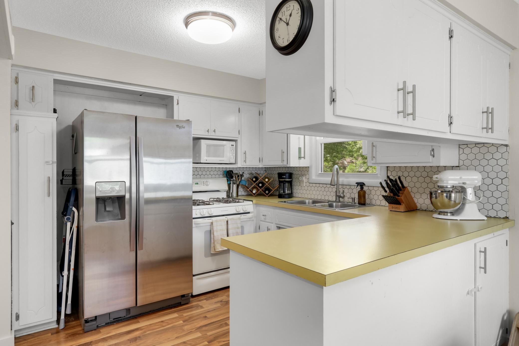 Kitchen has white painted cabinets and a tile backsplash
