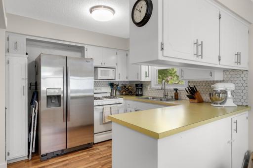 Kitchen has white painted cabinets and a tile backsplash