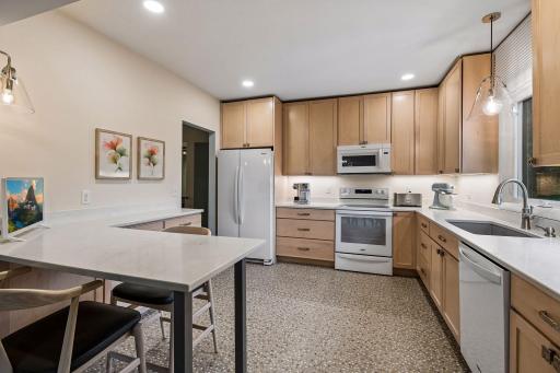 Beautifully updated kitchen features Maple cabinetry with a champagne finish and Valencia quartz countertops.