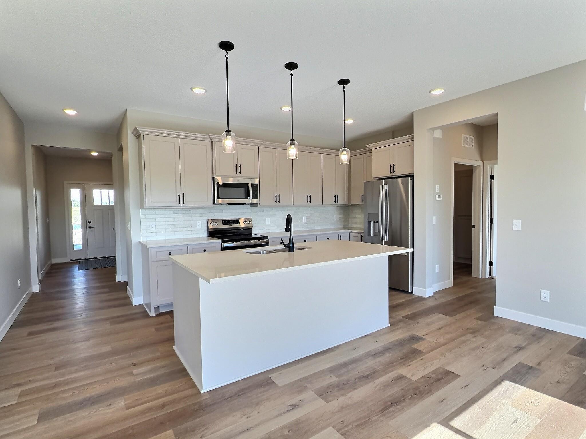 Open design to the kitchen with ample counter space on center island for your work station when prepping meals. Photo is of current model that is sold.