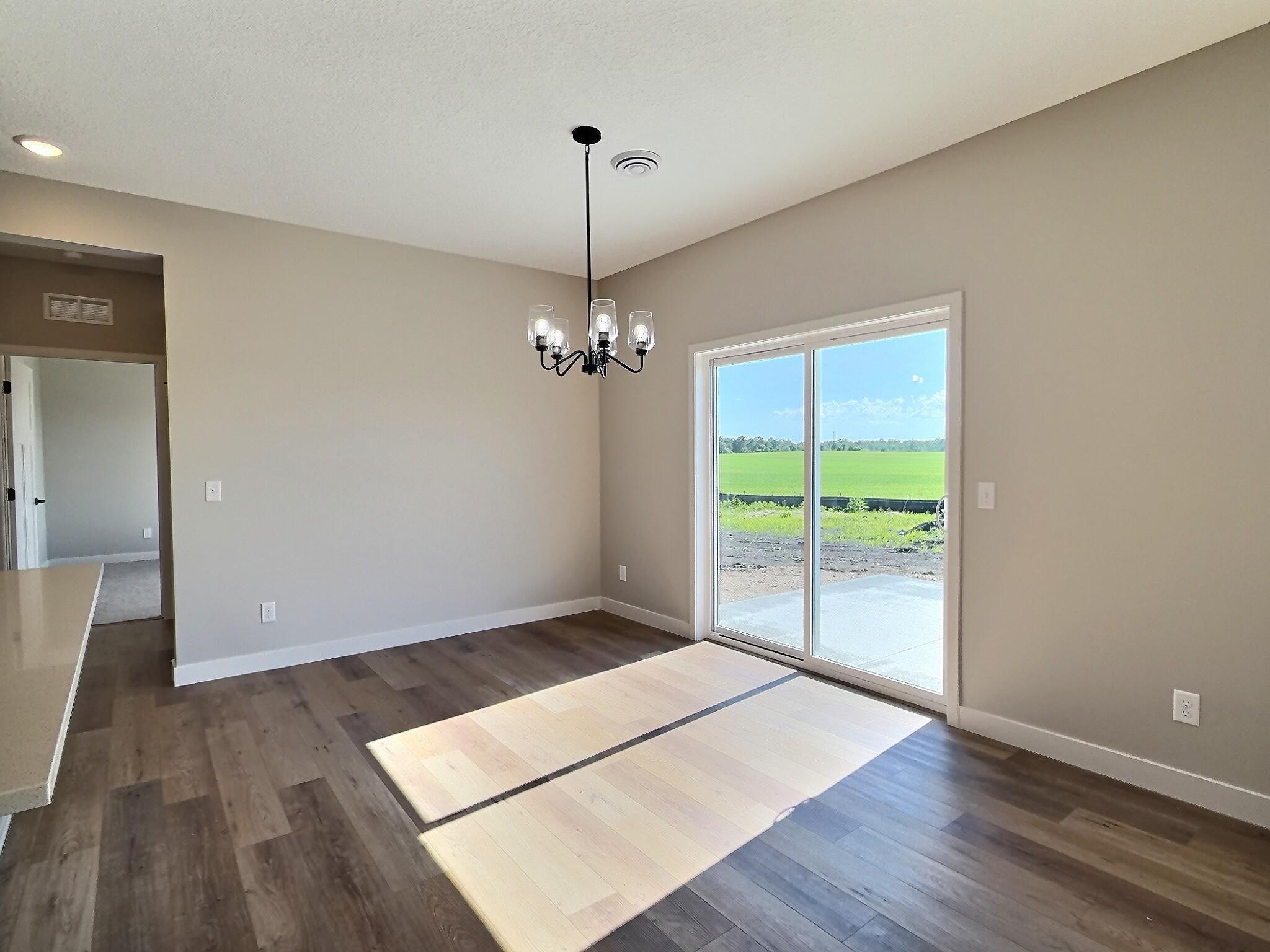 The dining room features patio doors that open to a concrete patio, offering a perfect view of the open countryside. Photo is of current model that is sold.