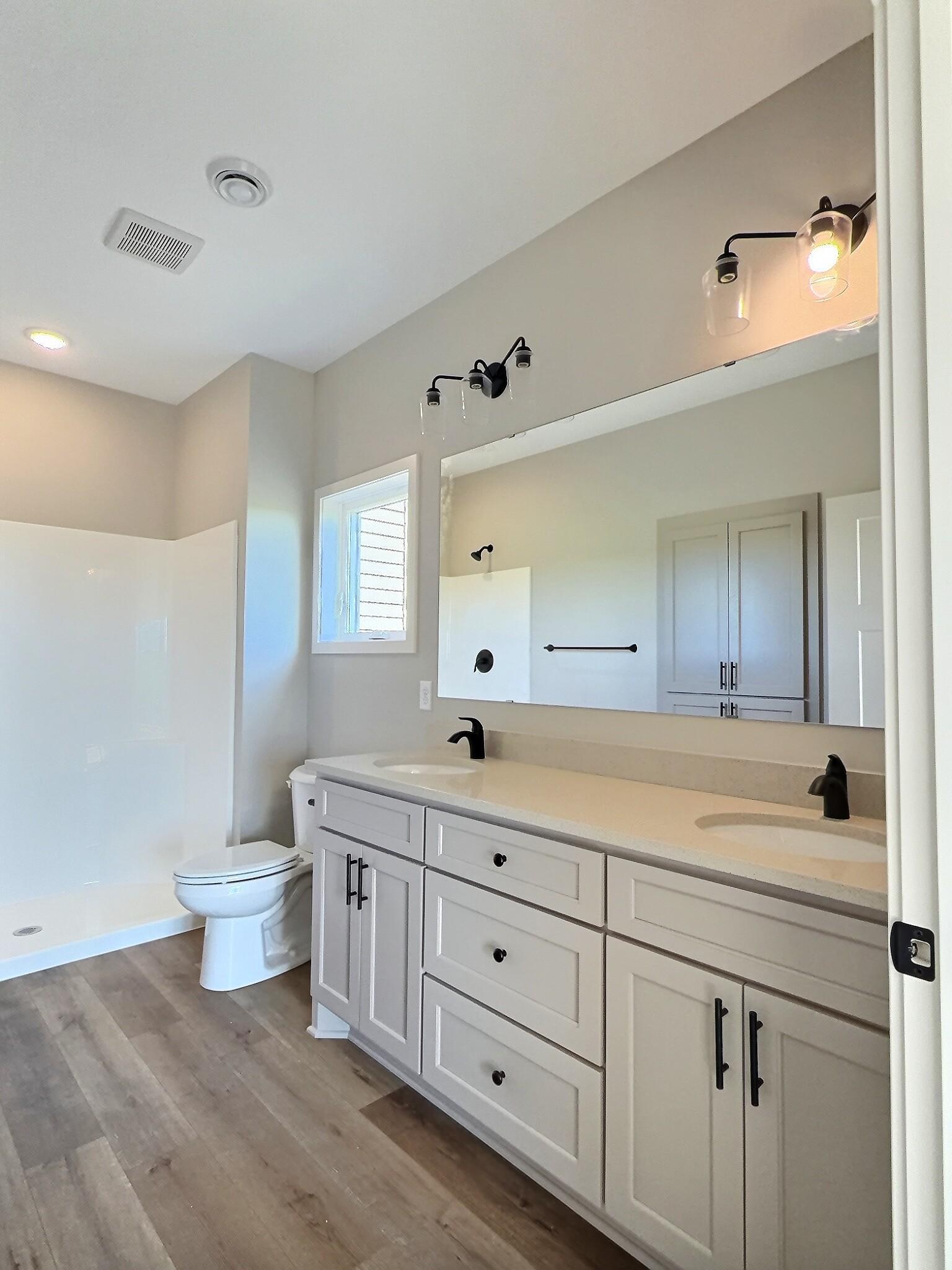 The walk in shower, double sinks and custom cabinets in the primary bathroom. Photo is of current model that is sold.