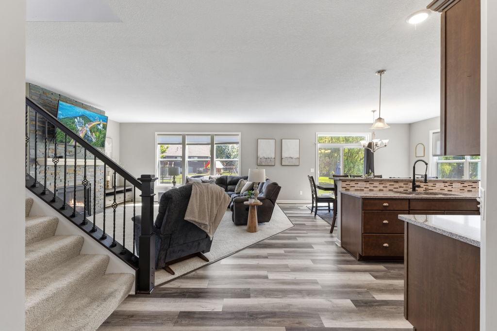 Front foyer walking into the main level living space. The space is surrounded with large windows overlooking the backyard. Stone surrounded fireplace, window treatments throughout, new kitchen/dining flooring.