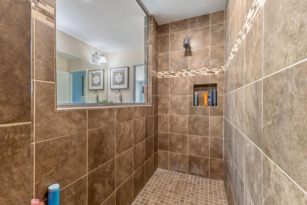 The stone shower has built-in shelving and built-in seats for comfort.