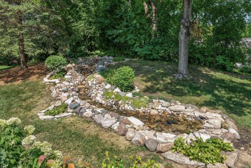 Thoughtfully designed landscaping and a picturesque waterfall transform the backyard into an unforgettable outdoor oasis.